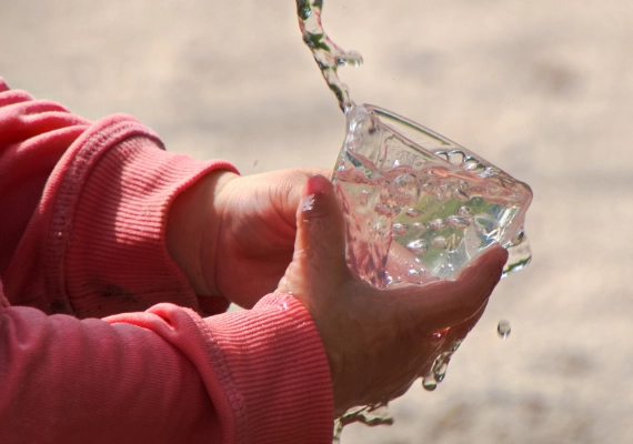 Person holding a glass as clean drinking water flows into it